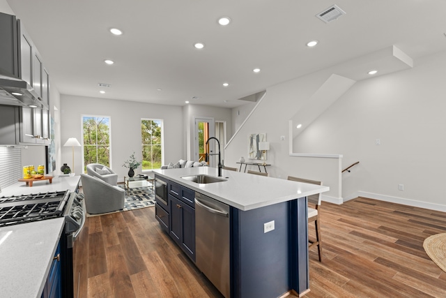 kitchen featuring sink, appliances with stainless steel finishes, dark hardwood / wood-style floors, and an island with sink