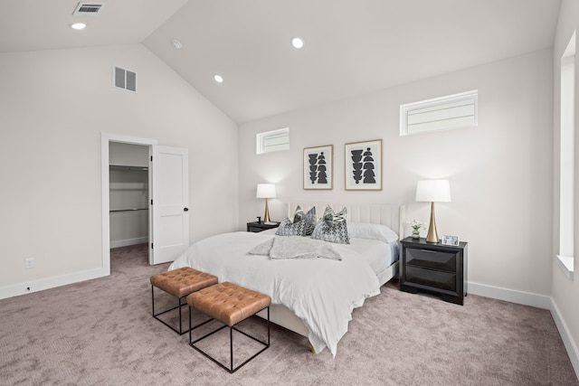 carpeted bedroom featuring a closet, a walk in closet, and high vaulted ceiling