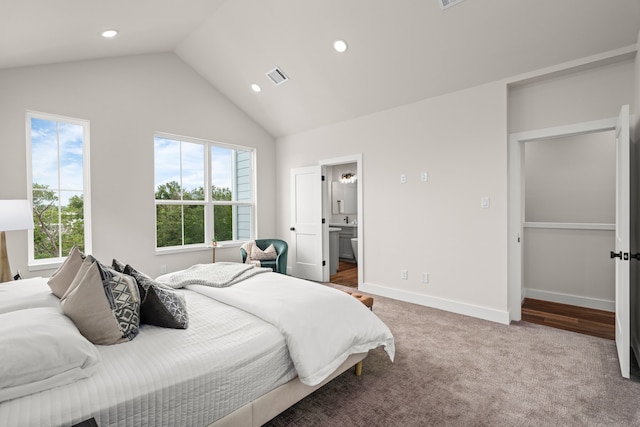 carpeted bedroom with ensuite bathroom and lofted ceiling