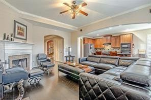 living room featuring ceiling fan, crown molding, and a fireplace