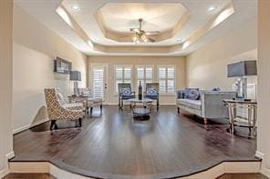 sitting room featuring ceiling fan, wood-type flooring, and a tray ceiling