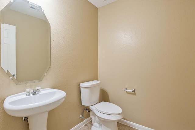 bathroom with toilet, tile patterned flooring, and sink