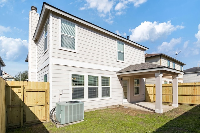 rear view of house with a patio area, a yard, and central AC