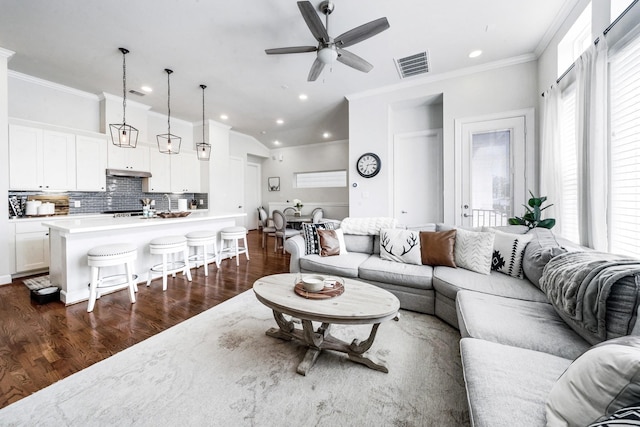 living room with dark hardwood / wood-style flooring, crown molding, and ceiling fan