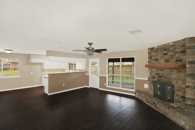 unfurnished living room featuring ceiling fan, dark wood-type flooring, and a brick fireplace