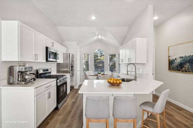 kitchen with a kitchen bar, appliances with stainless steel finishes, sink, and white cabinetry