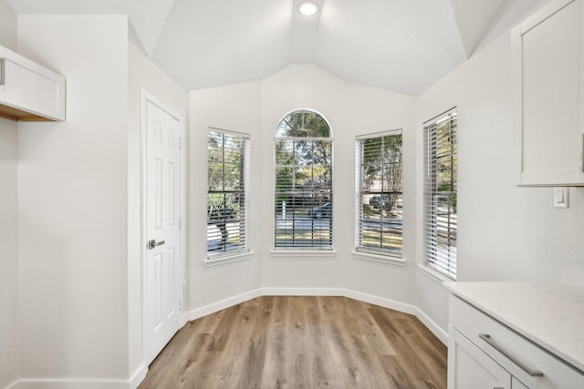 unfurnished dining area with lofted ceiling and light hardwood / wood-style floors