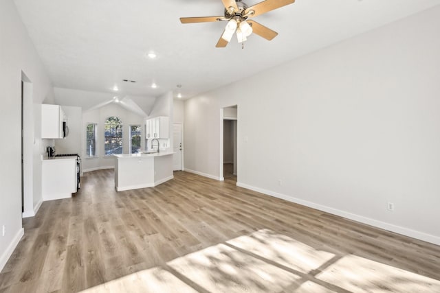 unfurnished living room featuring ceiling fan, light hardwood / wood-style floors, sink, and vaulted ceiling