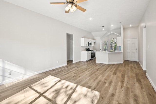 unfurnished living room with ceiling fan, sink, light hardwood / wood-style flooring, and lofted ceiling