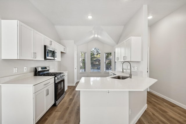 kitchen featuring appliances with stainless steel finishes, dark wood-type flooring, vaulted ceiling, white cabinets, and sink