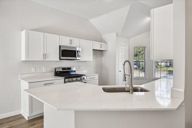 kitchen with kitchen peninsula, sink, stainless steel appliances, and white cabinetry