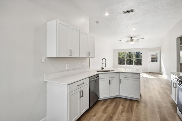 kitchen with kitchen peninsula, sink, stainless steel appliances, and white cabinetry