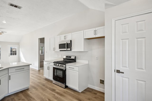 kitchen featuring light hardwood / wood-style floors, ceiling fan, stainless steel appliances, lofted ceiling, and white cabinets