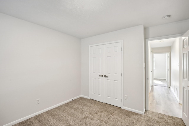 unfurnished bedroom featuring light colored carpet and a closet