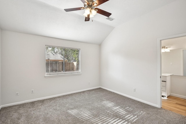 carpeted spare room featuring ceiling fan and vaulted ceiling