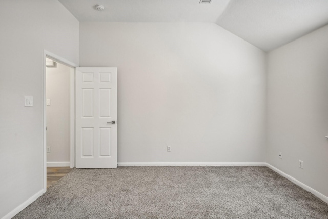 carpeted spare room featuring lofted ceiling