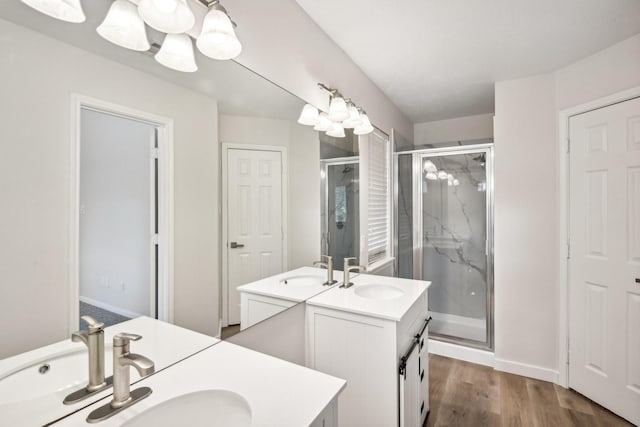 bathroom with an enclosed shower, vanity, an inviting chandelier, and hardwood / wood-style flooring