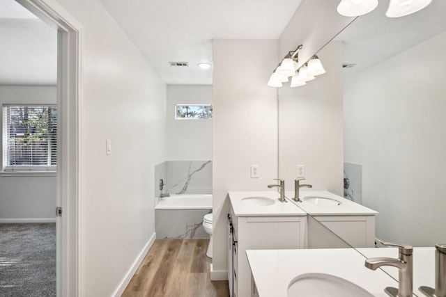 bathroom featuring toilet, vanity, a bathing tub, and hardwood / wood-style floors