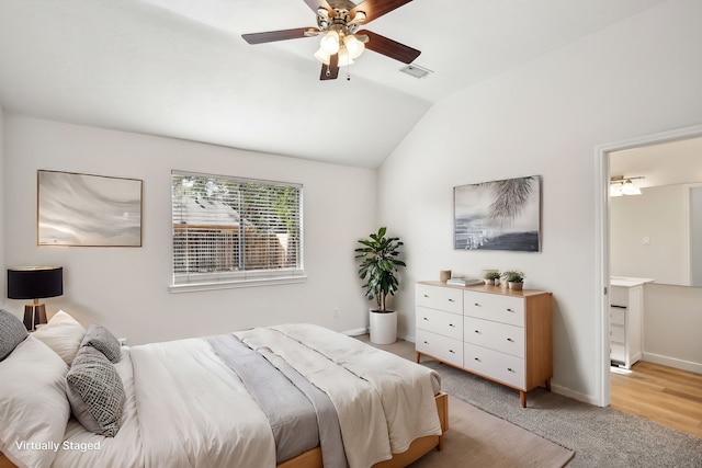 bedroom with ceiling fan, light colored carpet, ensuite bathroom, and vaulted ceiling