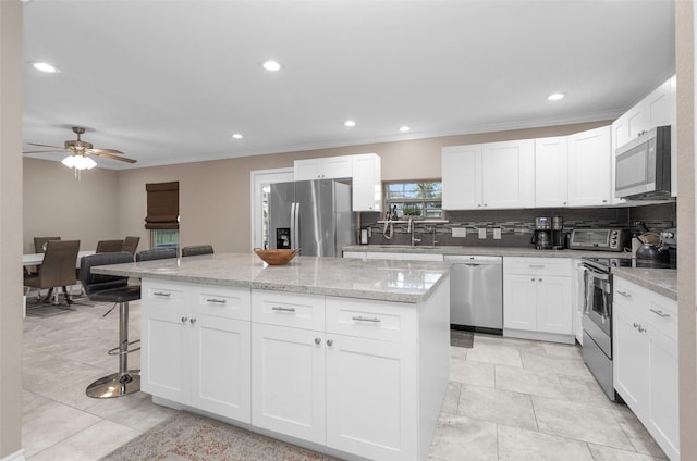 kitchen featuring white cabinets, appliances with stainless steel finishes, sink, and a kitchen island