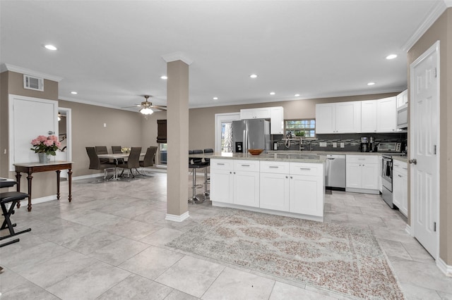 kitchen with white cabinetry, crown molding, a center island, appliances with stainless steel finishes, and ceiling fan