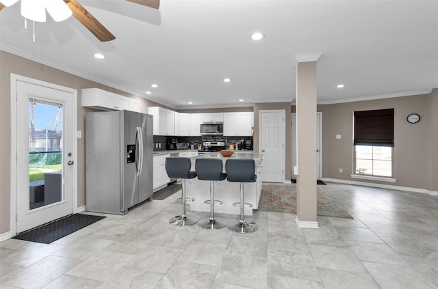 kitchen featuring backsplash, white cabinets, a kitchen breakfast bar, a center island, and stainless steel appliances