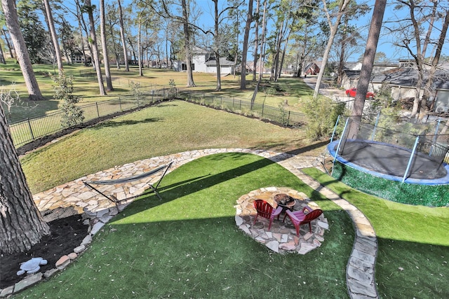 view of yard featuring a trampoline and an outdoor fire pit