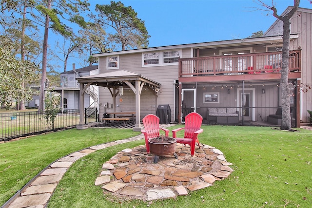 rear view of property featuring a patio area, a gazebo, a balcony, a lawn, and a fire pit