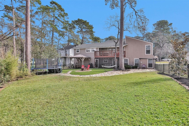 rear view of house with a trampoline, a yard, and a gazebo