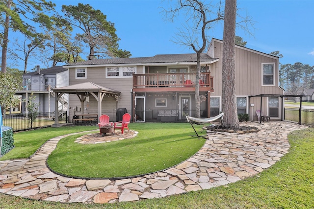 rear view of house featuring a fire pit, a yard, a gazebo, and a balcony