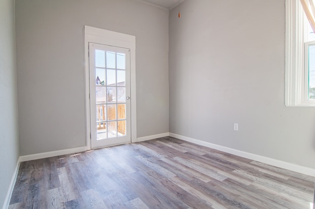 spare room with plenty of natural light, baseboards, and wood finished floors