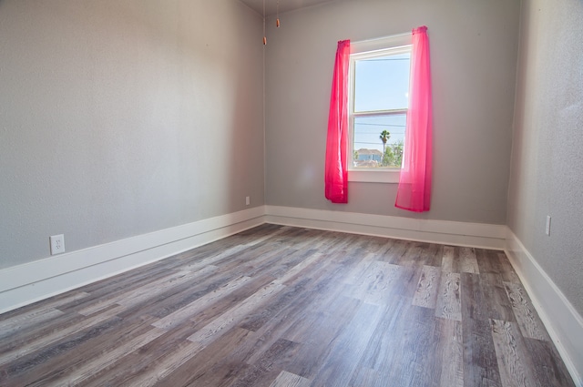 spare room featuring baseboards and wood finished floors