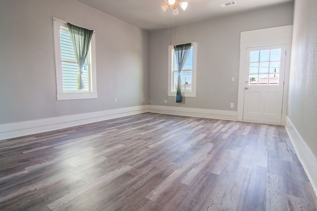 spare room featuring wood finished floors, visible vents, and baseboards