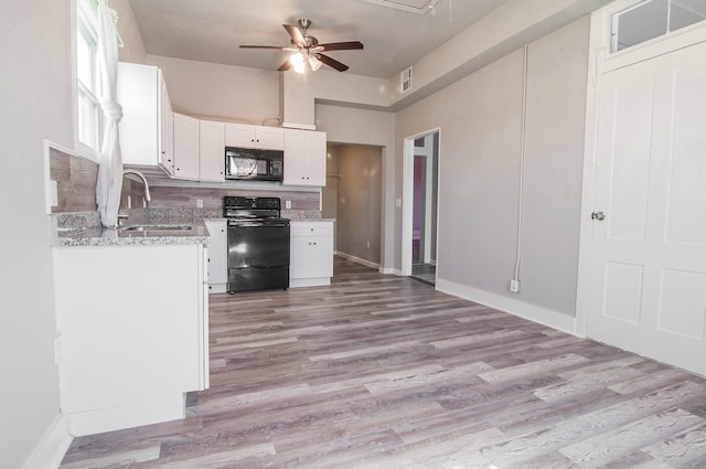 kitchen with white cabinetry, black appliances, light wood finished floors, and a sink