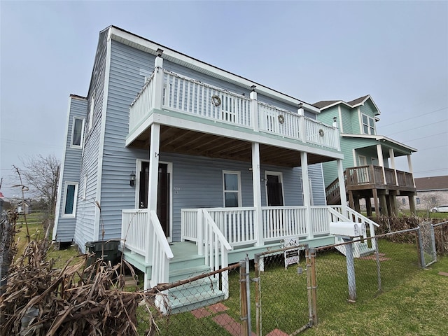 view of front facade featuring a gate, covered porch, a front yard, and fence