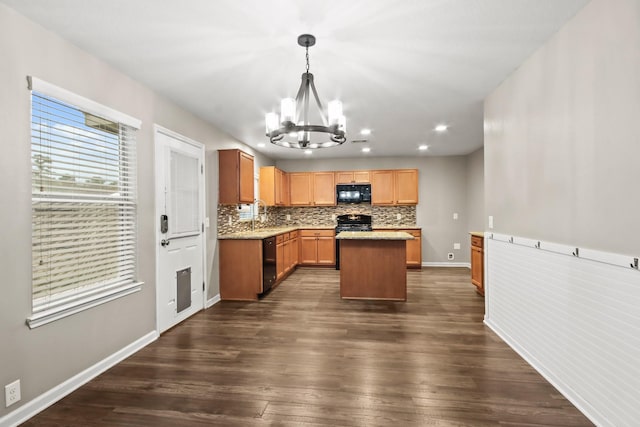 kitchen featuring pendant lighting, dark wood-type flooring, a kitchen island, black appliances, and an inviting chandelier