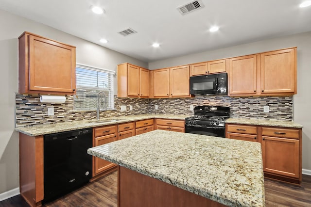 kitchen with sink, black appliances, light stone countertops, and a kitchen island