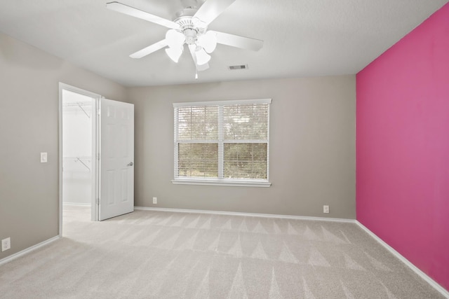 empty room featuring ceiling fan and light carpet