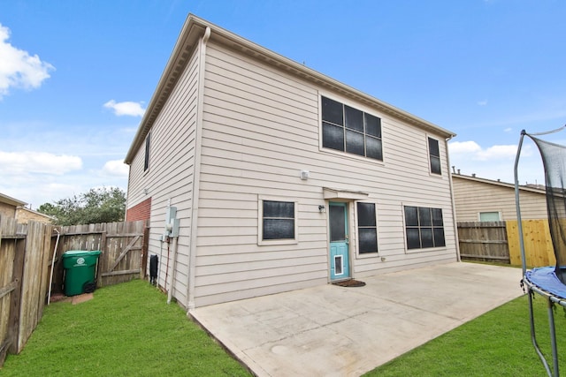 rear view of house with a lawn, a patio, and a trampoline