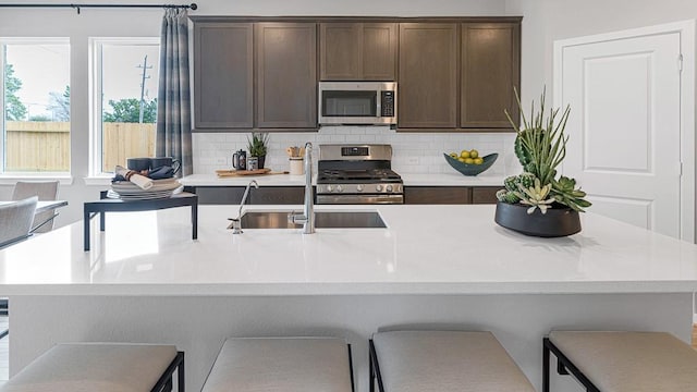 kitchen featuring stainless steel appliances, light countertops, backsplash, and dark brown cabinets