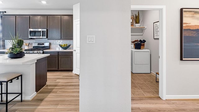 kitchen featuring washer / clothes dryer, light countertops, decorative backsplash, appliances with stainless steel finishes, and light wood-style floors