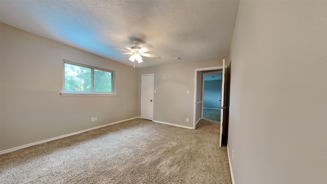 spare room featuring ceiling fan, light colored carpet, and a textured ceiling