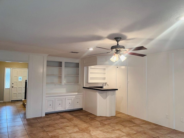 kitchen featuring ceiling fan, kitchen peninsula, white cabinetry, a textured ceiling, and built in shelves