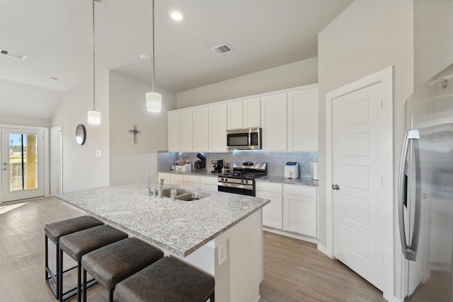 kitchen with white cabinetry, a center island with sink, appliances with stainless steel finishes, hanging light fixtures, and sink