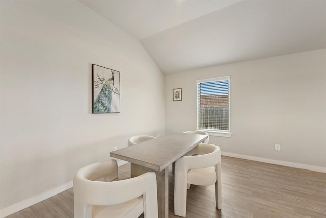 dining area with light wood-type flooring and vaulted ceiling