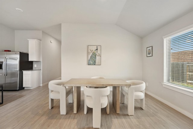 dining space with vaulted ceiling, a healthy amount of sunlight, and light hardwood / wood-style floors