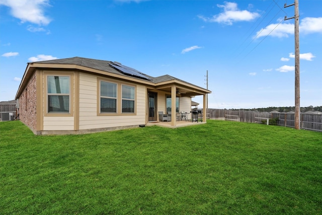 rear view of house with a lawn, central AC, solar panels, and a patio