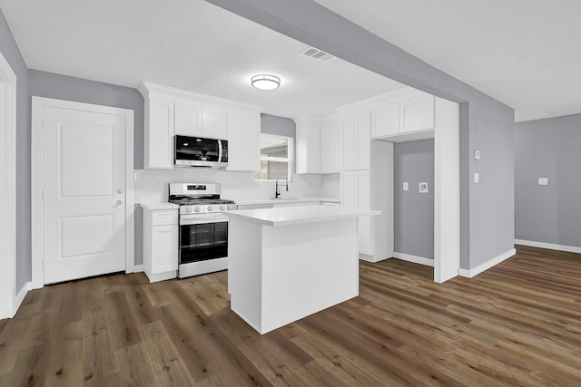 kitchen with stainless steel appliances, white cabinetry, a kitchen island, and sink