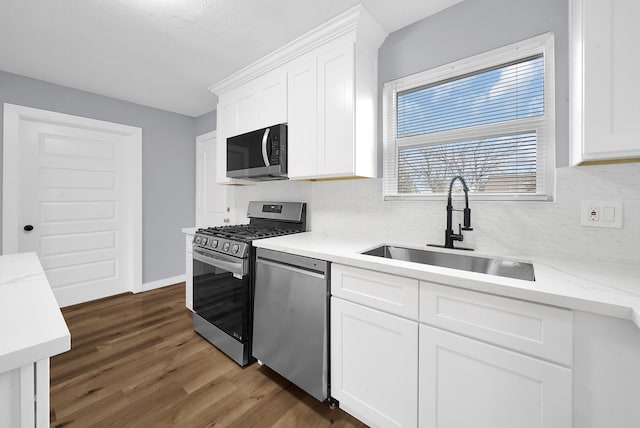 kitchen featuring light stone countertops, appliances with stainless steel finishes, white cabinetry, sink, and dark hardwood / wood-style floors