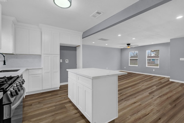 kitchen with ceiling fan, gas stove, a center island, sink, and white cabinets